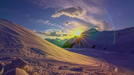Hyperlapse-shot-of-beautiful-sunset-hiding-between-snowy-mountains-in-ski-area-during-winter---Empty-Slope-in-the-evening