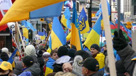 Multitud-De-Personas-Protestando-Por-La-Invasión-De-Rusia-En-Ucrania,-Manifestantes-Sosteniendo-Banderas-Ucranianas-En-Apoyo---Tiro-Firme