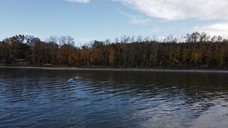 Drone-footage-of-a-caucasian-woman-paddling-a-blue-kayak-over-Buffalo-lake-on-a-cloudy-autumn-day