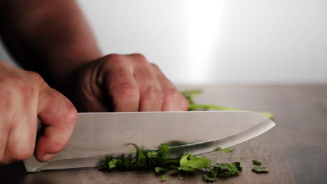 Professional-chef-cutting-parsley-on-wood-chopping-block