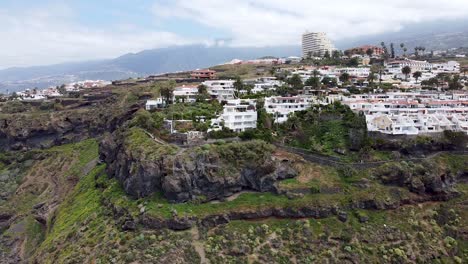 Aerial-drone-view-of-residential-and-hotel-complexes-next-to-the-coastline-in-Northern-Tenerife,-Canary-Islands,-Spain