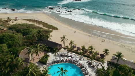 Beautiful-beach-club-surrounded-by-palm-trees-overlooking-a-white-sand-beach-in-Oaxaca-Mexico