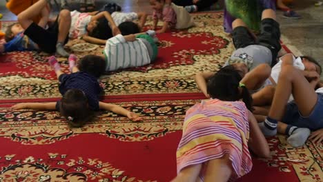 Asian-Children-rolling-around-and-playing-on-beautiful-red-Persian-carpet