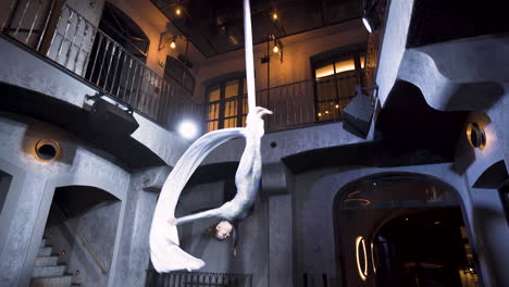 Female-aerialist-performing-a-headlong-drop-on-silks-in-a-club-venue
