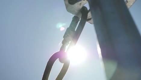 carabiner-on-a-scaffold-with-his-rope-on-a-construction-site-for-security-in-a-bright-summer-day-with-the-sun-making-flare