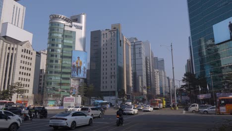 Belebte-Kreuzung-Mit-Starkem-Verkehr-Am-Bahnhof-Gangnam-Im-Stadtzentrum-Von-Seoul-Mit-Urbaner-Skyline-Und-Riesigen-Digitalen-Werbedisplays-An-Gebäuden
