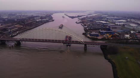 Aerial-View-Of-Maas-And-FPS-RIJN-Cargo-Ships-Passing-Underneath-Brug-Over-De-Noord-On-Cloudy-Afternoon