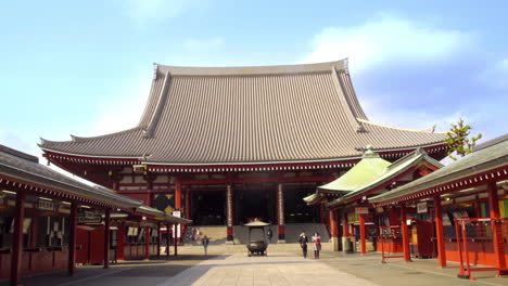 ASAKUSA,-TOKYO,-JAPAN,-circa-April-2020:-fortune-and-amulet-shops-lined-both-sides-of-the-approach-to-traditional-Japanese-temple,-where-worshippers-walking-on-a-peaceful-sunny-spring-day