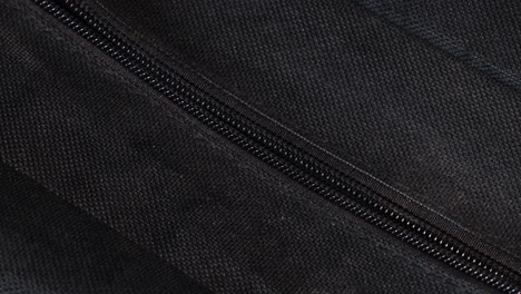 Opening-the-zipper-of-a-dark,-black-bag