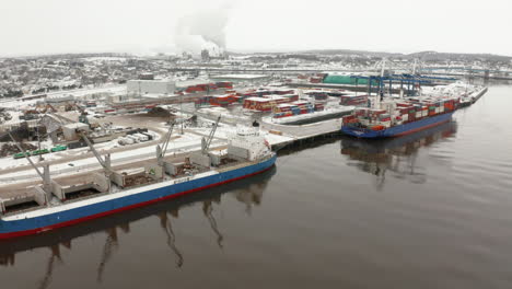 Aerial-view-of-two-large-freighters-docked-in-port-on-a-snowy,-winter-day