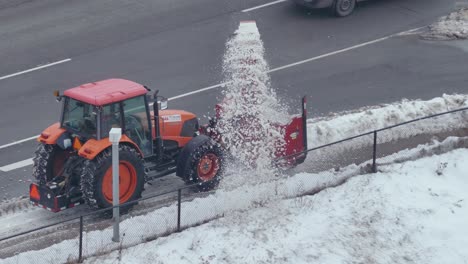 Orange-Tractor-Cleaning-Snow-With-Plow-And-Thrower-Beside-Road-In-Toronto,-Canada