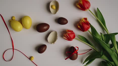 Top-shot-of-Orange-tulips-flowers-on-white-background-with-brown-and-yellow-colored-easter-eggs