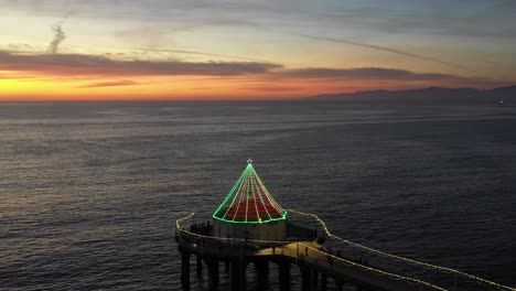 Roundhouse-Aquarium-At-Manhattan-Beach-Pier-Illuminated-With-Lights-At-Sunset---aerial-drone-shot