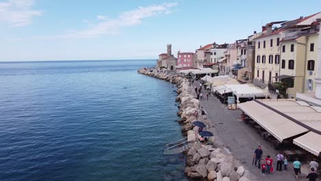 Piran,-Istria,-Slovenia---Aerial-Drone-View-of-the-Boulevard-with-Walking-Touristst,-Restaurants-and-Church