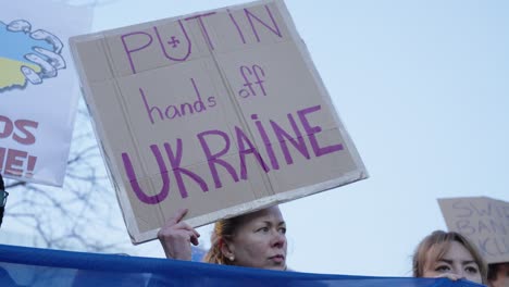 Close-up-of-protester-with-banner-against-Russia's-invasion-of-Ukraine-at-twilight