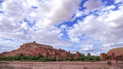 Time-lapse-shot-of-Aït-Ben-Haddou-City-located-on-hill-in-Atlas-Mountains-of-Morocco---People-walking-towards-village---Clouds-flying-at-sky---UNESCO-World-Heritage