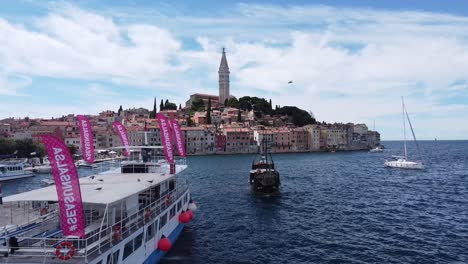 Rovinj-En-Istria,-Croacia---Barcos-Turísticos-En-El-Bulevar-Y-El-Casco-Antiguo-De-Colorfol-Con-La-Torre-De-La-Iglesia-En-El-Mar-Adriático