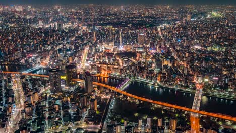 Vista-De-Skytree-De-Tokio-Japón-Desde-La-Torre-De-Observación-En-Sumida-En-El-Lapso-De-Tiempo-Nocturno-Mirando-La-Ciudad-Debajo-Con-Autos-Y-Trenes-Pasando-Sobre-El-Río-En-La-Oscuridad