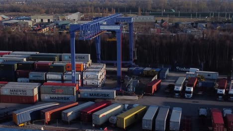 Shipping-container-crane-lift-unloading-heavy-cargo-export-crate-containers-in-shipyard-aerial-slowly-left-panning-shot