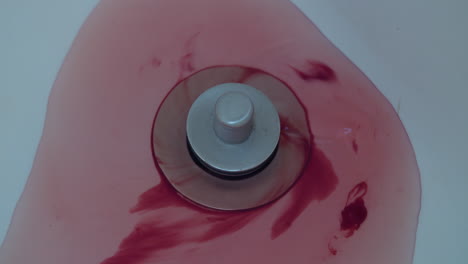 Close-up-of-blood-and-water-washing-down-a-shower-drain