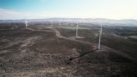 Wide-angle-of-a-vast-wind-powered-electric-turbine-sustainable-green-energy-farm-in-a-desert,-aerial