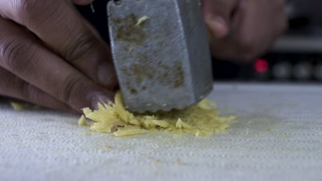 Metal-Tenderizer-Being-Used-To-Crush-Fresh-Ginger-On-Cutting-Board