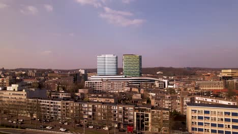 Aerial-backwards-movement-high-rise-contemporary-modern-architecture-of-central-bus-and-train-station-rising-above-the-city-revealing-roundabout-traffic-crossing-with-the-river-Rijn-in-the-foreground