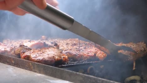 Tight-close-up-shot-of-tasty-meat-being-flipped-on-a-barbecue-with-cooking-tongs