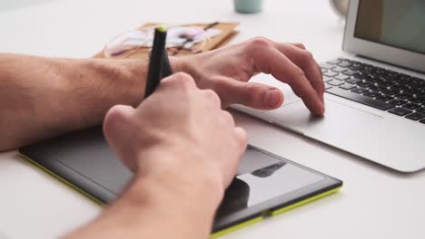 Professional-designer-using-a-digital-graphic-tablet-and-an-electronic-pen-to-work-on-an-office-desk