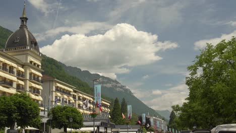 Lujoso-Hotel-Victoria-Jungfrau,-Montañas-De-Los-Alpes-Cubiertas-De-Vegetación-En-El-Fondo-De-Un-Cielo-Nublado,-Interlanken,-Suiza