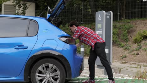 Young-man-prepares-electric-car-for-charging-on-outdoor-Energa-station-in-Poland
