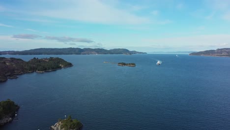 Torghatten-ferry-Flatoy-is-approaching-Sandvikvaag-with-Bjornafjorden-sea-in-background---Static-aerial-overview-Norway