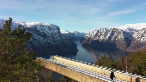 Tourist-walking-back-to-his-car-after-visiting-Stegastein-viewpoint-in-Aurland---Static-aerial-of-attraction-in-beautiful-sunny-weather