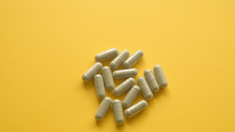 Close-Up-Shot-Of-Right-Hand-Picking-Up-One-Lions-Mane-Supplement-Pill-From-Yellow-Table