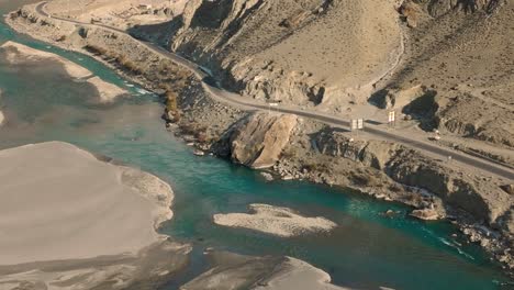 Turquoise-Ghizer-river-flowing-through-forest-in-Gahkuch,-surrounded-by-Hindu-Kush-mountain-range