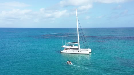 Tourists-ferried-to-catamaran-with-inflatable-boat,-azure-blue-Caribbean
