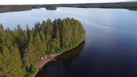 Drone-Shot-of-an-Island-in-the-Middle-of-a-Northern-Lake-with-a-Kayak-on-the-Shore