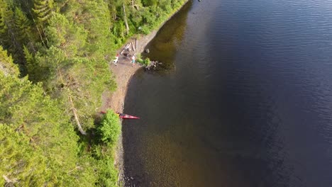 Drohnenaufnahme-Einer-Insel-Inmitten-Eines-Nördlichen-Sees-Mit-Einem-Kajak-Am-Ufer