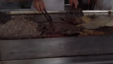Slow-motion-of-meat-being-flipped-at-grill-for-Mexican-Taco,-handheld