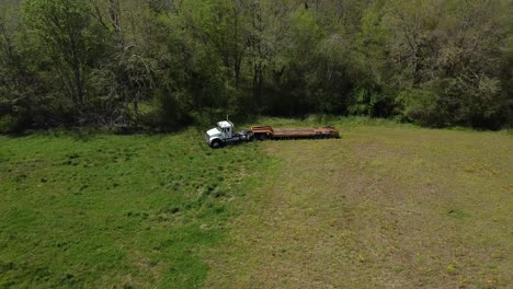 Aerial-Abandoned-Cargo-Truck-At-The-Edge-Of-A-Forest-In-A-Green-Field