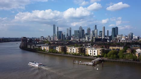 Static-drone-shot-of-Canary-Wharf-in-London-with-boat-on-River-Thames