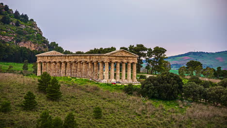 View-of-tourists-visiting-the-Doric-temple-of-Segesta,-Province-of-Trapani,-Sicily,-Italy-at-daytime-in-timelapse,-surrounded-by-hilly-terrain