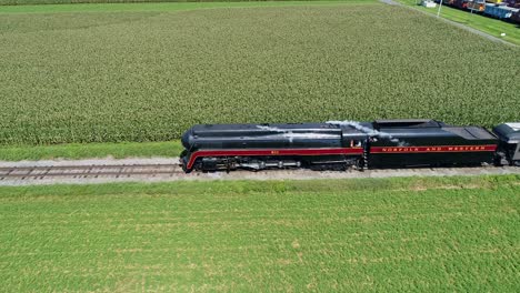 An-Aerial-View-Traveling-to-the-Side-of-An-Antique-Steam-Passenger-Train,-Blowing-Smoke-Traveling-Thru-Corn-Fields-and-Rich-Farmlands-on-a-Cloudless-Summer-Day