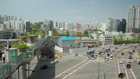 People-walking-on-Seoullo-7017-skygarden-and-traffic-at-Tongil-ro-and-Sejong-daero-crossroad-with-Seoul-Panorama