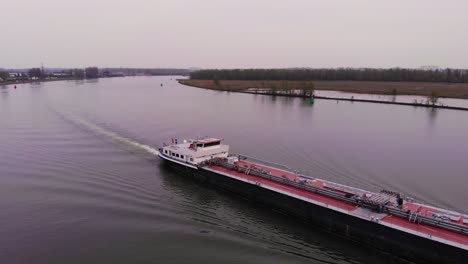 Aerial-Along-Starboard-Side-Of-Monika-Inland-Tanker-Ship-Navigating-Oude-Maas-On-Cloudy-Day
