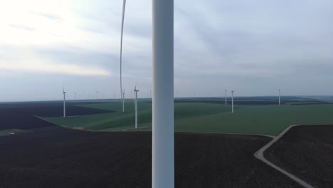 Windmill-Farm-on-Field,-Dolly-in-Aerial-View,-Passing-Wind-Turbine,-Wide-Shot