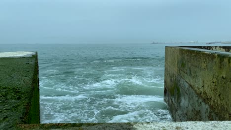 A-stormy-ocean-water-slams-against-a-concrete-breakwater---Pontão-da-Barra-do-Douro---Molhe-Norte,-Porto,-Portugal---slowmotion