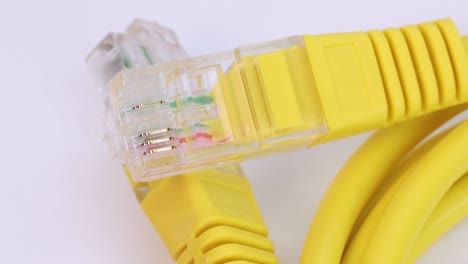 Makroaufnahme-Eines-Ethernet-Kabels-Aus-Gelbem-Kunststoff,-Das-Sich-Auf-Weißer-Oberfläche-Dreht,-Nahaufnahme-Von-Oben-In-4k