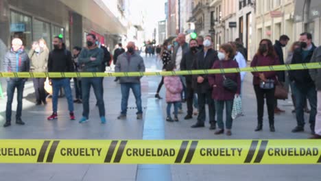 Zuschauer-Stehen-Hinter-Einem-Gelben-Band-Mit-Dem-Wort-&quot;Grausamkeit&quot;-Während-Einer-Demonstration-Einer-Pro-Tierrechtsgruppe-Animanaturalis-Gegen-Die-Verwendung-Von-Tieren-Im-Pelz-In-Madrid,-Spanien