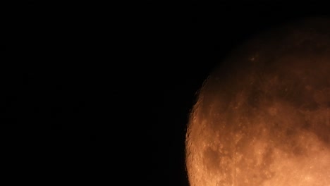 Extreme-close-up-shot-of-orange-full-moon-in-dark-black-sky